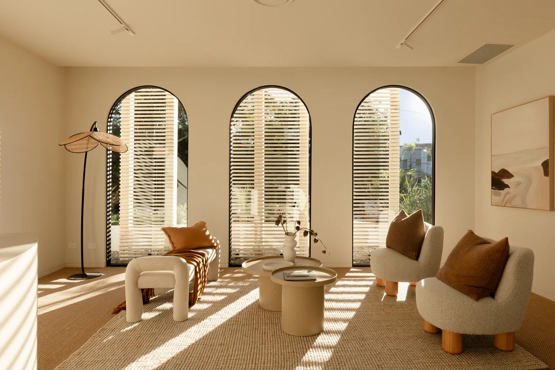 Bright room with three arched aluminium windows and timber shutters